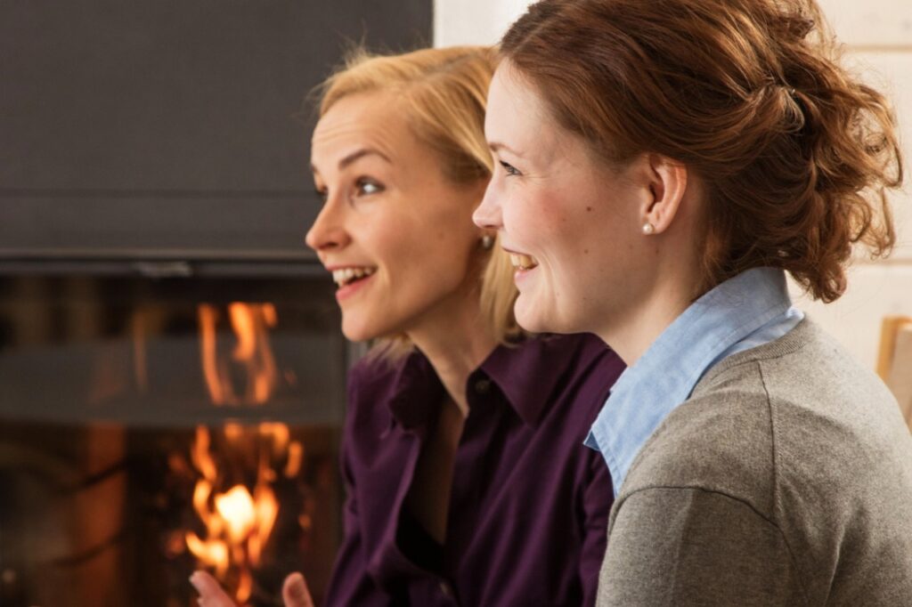 Deux femmes discutent devant une cheminée — Coucouning vs Cocooning, illustration du bien-être relationnel.
